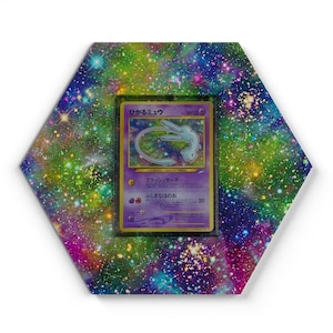 Könnte beinhalten: Ein sechseckiger Bilderrahmen mit einem lebendigen Galaxie-Druck in Blau-, Grün- und Violetttönen, der eine japanische Mew-Sammelkarte enthält. Die Karte zeigt den Text "ひかるミュウ" und "HP50" mit einer zentralen Abbildung der Figur.