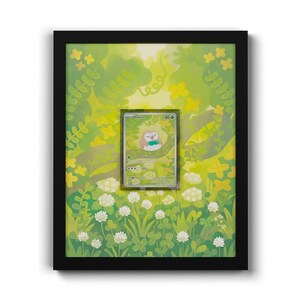 May include: A black rectangular frame containing a Rowlet trading card centered against a vibrant green background illustration of a forest with white clover flowers, leafy branches, and soft yellow sunlight filtering through the trees.