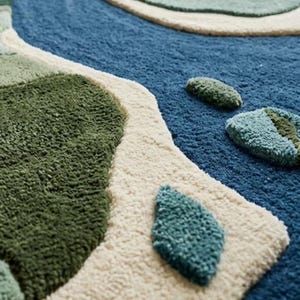 May include: A tufted area rug featuring a textured, abstract landscape design. The rug displays organic shapes in shades of deep forest green, sage green, and cream, set against a prominent, winding river pattern in a rich, deep blue color.