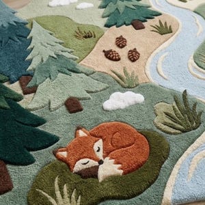 May include: A tufted area rug featuring a forest landscape with a sleeping orange fox, evergreen trees in shades of dark and light green, brown pinecones, white clouds, and a winding light blue river. The design includes textured grassy patches.