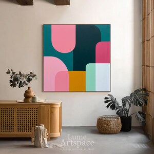 May include: Abstract geometric wall art featuring a vibrant composition of shapes in pink, teal, mustard yellow, and mint green. The artwork is framed in a gold tone and hangs on a neutral wall. The text "Lume Artspace" is visible in the lower right corner.
