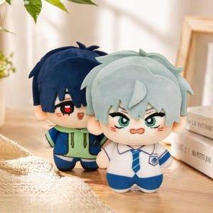 May include: Two plush dolls with anime-style features. One doll has blue hair and a green and blue outfit. The other doll has light blue hair and a white and blue school uniform. Both dolls have detailed facial features.