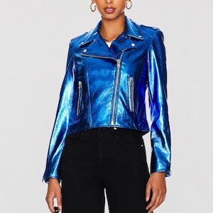 May include: A metallic blue motorcycle jacket with a silver zipper closure and multiple zippered pockets. The jacket has a classic asymmetrical design with a notched collar and long sleeves. The jacket is worn with black pants.
