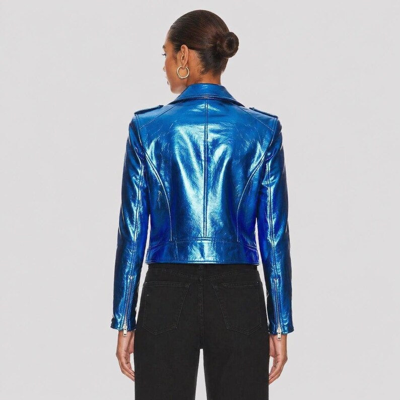May include: A metallic blue motorcycle jacket with a shiny finish. The jacket has a classic design with a notched collar, zippered pockets, and a fitted silhouette. The model is wearing black jeans.