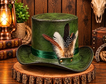 May include: A dark green top hat with a distressed leather-like finish, featuring a matching green satin ribbon band and a decorative cluster of assorted brown, white, and black spotted feathers secured by a small leather strap with two brass studs.