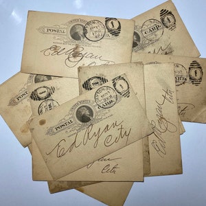 May include: A collection of antique postal cards. The cards are beige with black ink stamps and handwritten script. Each card features a portrait of a man and the words "United States Postal" and "Card".