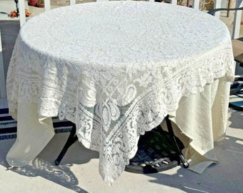 Mantel redondo de encaje vintage blanco con medallón floral, estilo rústico costero.