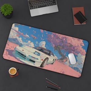 Può includere: Tappetino per mouse rettangolare con un'auto sportiva bianca su uno sfondo di fiori di ciliegio rosa, cielo blu e nuvole bianche. Un mouse per computer è sulla destra.