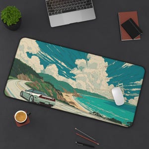 Pode incluir: Um grande tapete de rato retangular com uma ilustração cénica de um carro desportivo branco a conduzir numa estrada costeira. A obra de arte inclui um céu azul com nuvens, colinas verdes e água turquesa. Um laptop, um rato e outros itens de mesa são visíveis.
