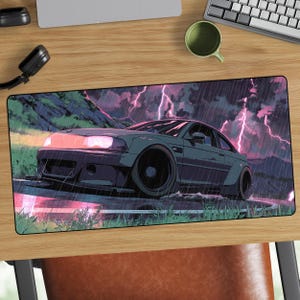 May include: A rectangular mousepad featuring a stylized illustration of a dark gray sports car driving on a wet road during a thunderstorm. The background shows mountains, rain, and pink lightning bolts. The car has black wheels and glowing headlights.