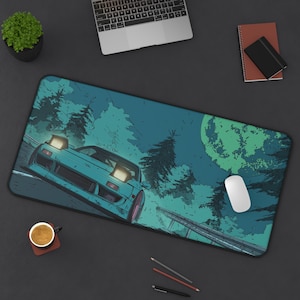 May include: A teal and blue desk mat featuring a stylized illustration of a sports car racing on a road at night. The design includes a large moon, trees, and a road barrier. A white mouse is on the mat.