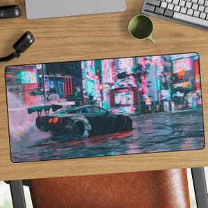 May include: Black and gray gaming mousepad featuring a drifting sports car on a wet city street at night. The car is emitting smoke, and the background shows neon lights and buildings. The mousepad is rectangular.