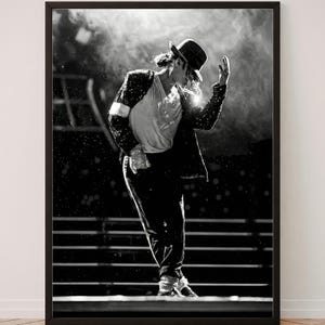 Puede incluir: Una impresión de arte mural enmarcada en blanco y negro que muestra a un artista con una chaqueta de lentejuelas, camisa blanca, pantalones oscuros y un sombrero fedora. La figura está en una pose de baile dinámica con una mano levantada.