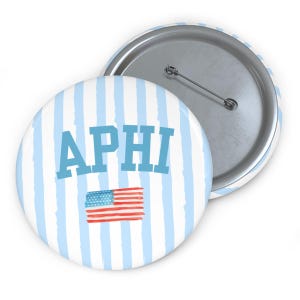 Könnte beinhalten: Ein runder Ansteckbutton mit einem hellblau-weißen vertikalen Streifenmuster. Der Text APHI ist in großen blauen Buchstaben über einer kleinen Illustration im Aquarellstil der amerikanischen Flagge in Rot, Weiß und Blau abgebildet.