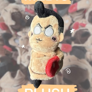 Puede incluir: Un peluche que representa a un personaje con cabello negro, gafas redondas y tez bronceada. El personaje tiene una boca pequeña, mejillas sonrosadas y viste una prenda color canela con un acento circular rojo. El texto "hugging! MEDIC" y "PLUSH" es visible.