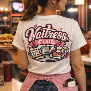 Könnte beinhalten: Weißes T-Shirt mit einem rosa-lila "Waitress Club"-Aufdruck auf dem Rücken. Die Grafik zeigt ein Tablett mit Speisen wie Burger, Pommes und Kuchen. Die Person trägt eine rosa Schürze und blaue Jeans.