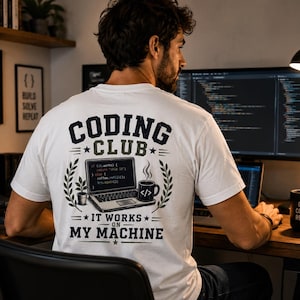 Könnte beinhalten: Ein weißes T-Shirt mit einem Aufdruck auf der Rückseite, der den Text "CODING CLUB" und "IT WORKS ON MY MACHINE" zeigt. Das Design enthält eine Illustration eines Laptops mit Code, eine Topfpflanze und eine Kaffeetasse mit einem Klammersymbol.