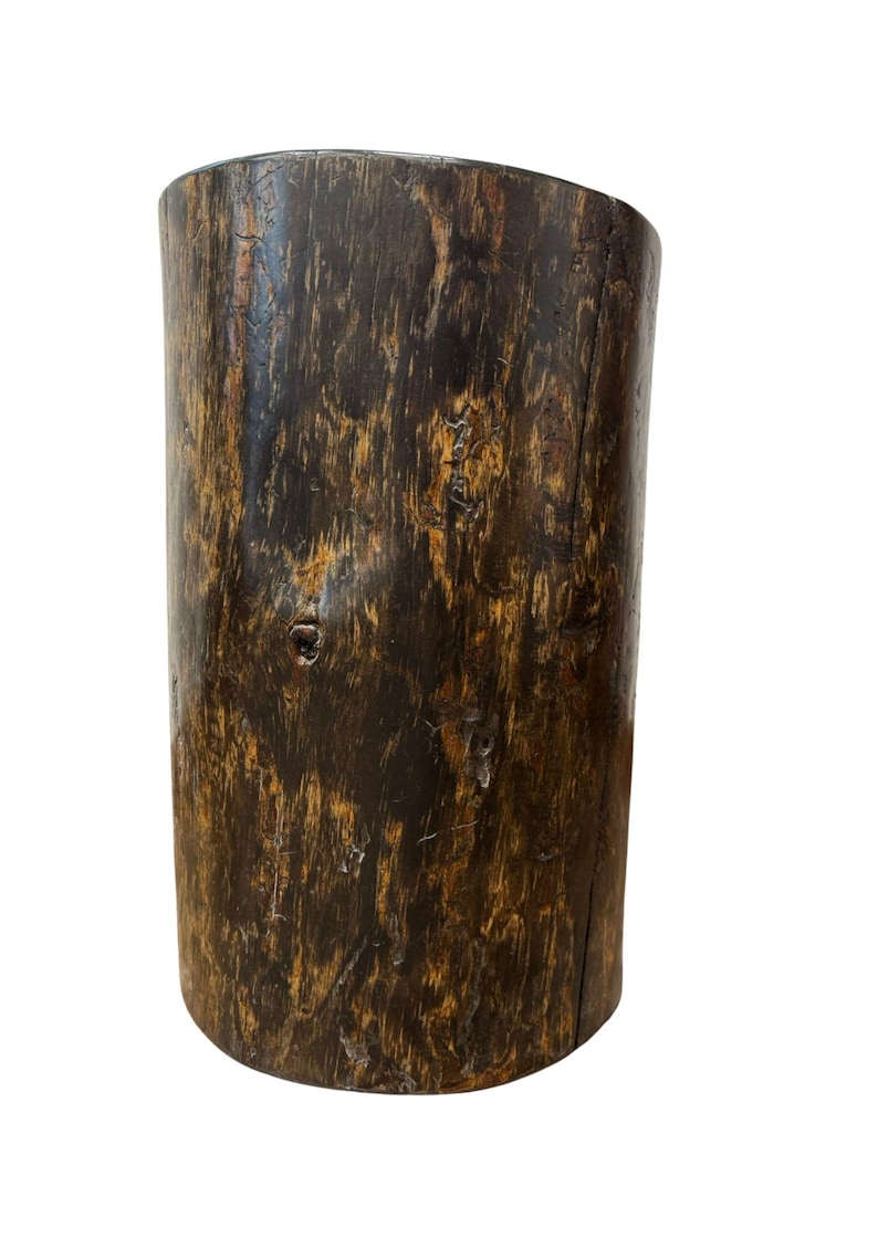 Puede incluir: Un taburete o pedestal cil&iacute;ndrico de madera con un acabado marr&oacute;n oscuro, que muestra patrones de vetas naturales, nudos y una superficie texturizada. El objeto tiene una parte superior plana y un aspecto vertical ligeramente desgastado.