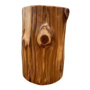 Pu&ograve; includere: Uno sgabello o tavolino cilindrico in legno ricavato da un unico tronco. La superficie presenta una finitura lucida color marrone chiaro e medio con venature naturali, fessure verticali e diversi nodi circolari di colore scuro.