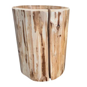 Pu&ograve; includere: Uno sgabello o tavolino cilindrico in legno ricavato da un unico tronco, caratterizzato da una finitura liscia e chiara con venature naturali del legno, striature marroni e una profonda spaccatura verticale lungo il lato.