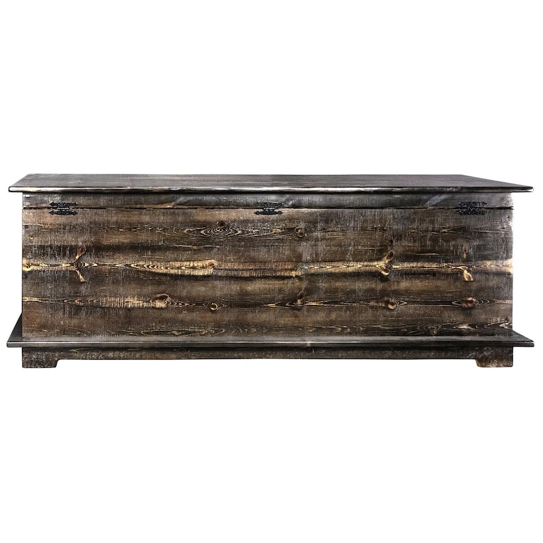 May include: A large, rustic wooden chest with a hinged lid. The chest is made of dark brown wood with visible grain and knots, and features metal hardware. The chest sits on a low base and has a rectangular shape, perfect for storage.