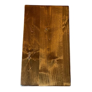 May include: A rectangular wooden board with a rich, warm brown stain. The wood grain is visible, and the surface has a smooth finish. The board is likely for use as a cutting board or serving tray.