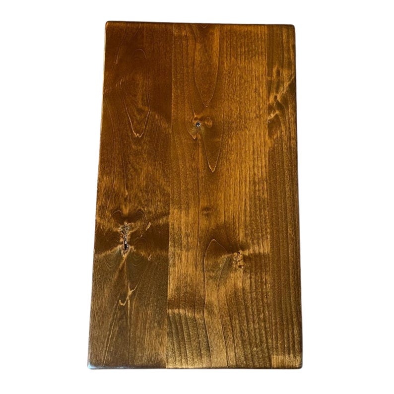 May include: A rectangular wooden board with a rich, warm brown stain. The wood grain is visible, and the surface has a smooth finish. The board is likely for use as a cutting board or serving tray.