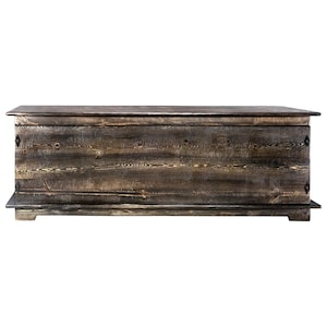 May include: A large, rectangular wooden chest with a dark, weathered finish. The chest has a flat top and a base, with visible wood grain and metal accents on the front. The design suggests a rustic or farmhouse style.