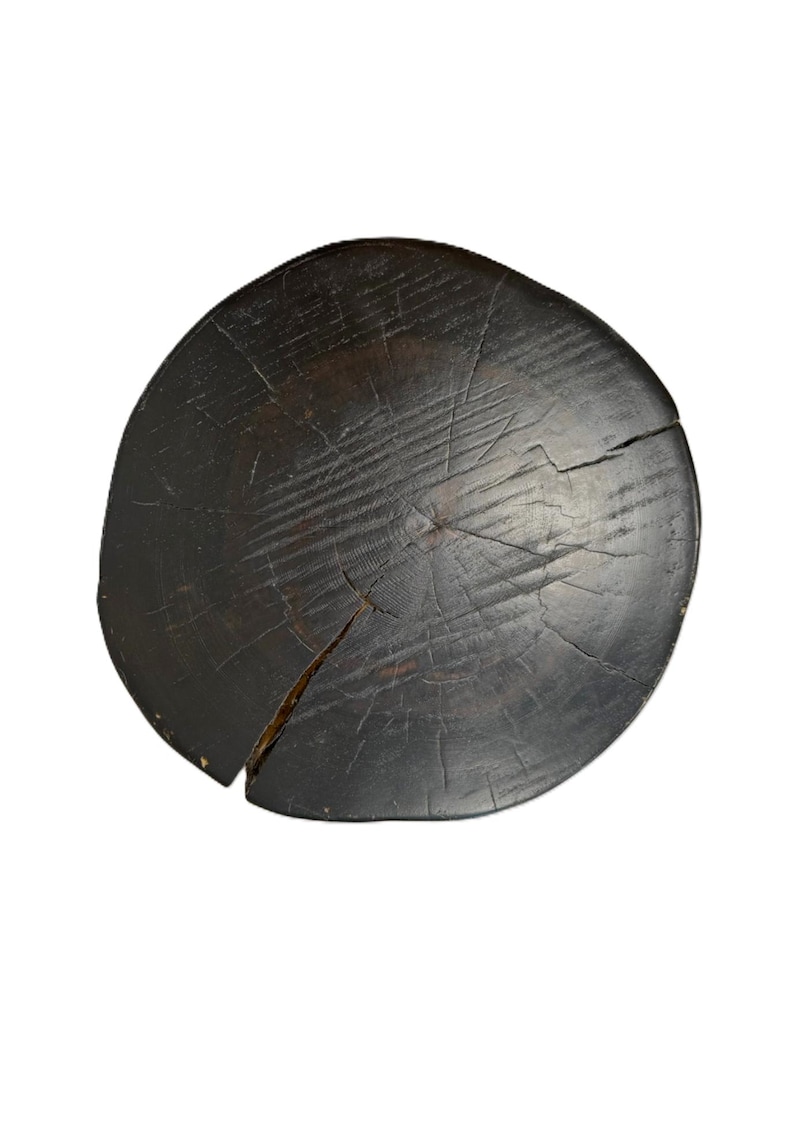 Puede incluir: Un asiento de taburete circular de madera con un acabado te&ntilde;ido en marr&oacute;n oscuro. La superficie muestra un patr&oacute;n de veta de madera natural prominente, anillos de crecimiento visibles y varias grietas estructurales profundas desde el centro.