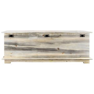 May include: A large, rectangular wooden storage chest with a light, weathered finish. The chest features black metal hinges and a simple, rustic design. The chest is elevated on a low base.