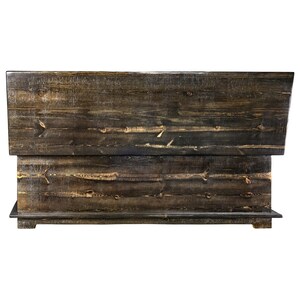 May include: A dark-stained wooden headboard with a layered design. The headboard displays visible wood grain and knots, enhancing its natural, textured appearance. The headboard is designed to be placed against a wall.