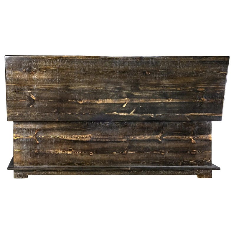 May include: A dark-stained wooden headboard with a layered design. The headboard displays visible wood grain and knots, enhancing its natural, textured appearance. The headboard is designed to be placed against a wall.