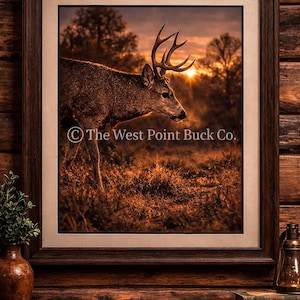 May include: A framed print depicting a deer in a field at sunset. The deer has large antlers and is facing left. The background shows a golden sunset and trees. The print is in a dark brown wooden frame. Text on the print reads "The West Point Buck Co."