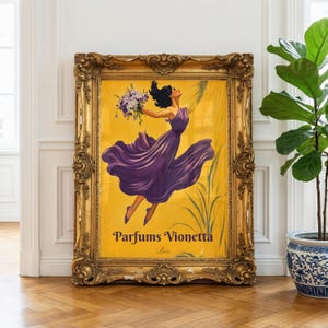 May include: A rectangular vintage-style advertisement poster in a heavy, ornate gold frame. The poster features a yellow background with a central illustration of a figure in a flowing purple dress holding a bouquet of purple flowers, with the text Parfums Vionetta Paris printed at the bottom.