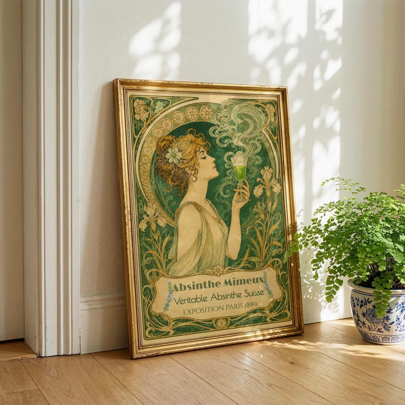 May include: A framed art print featuring a woman in a flowing dress holding a green glass of absinthe. The illustration includes swirling smoke, floral motifs, and the text: Absinthe Mimeux, Veritable Absinthe Suisse, EXPOSITION PARIS 1889.