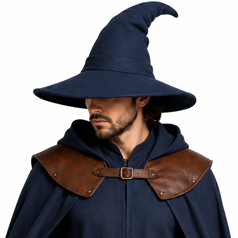 May include: A dark blue pointed wizard hat with a wide brim, paired with a dark blue hooded cloak featuring brown leather shoulder armor accents. The armor pieces are secured at the center with a brown leather strap and a metallic buckle.
