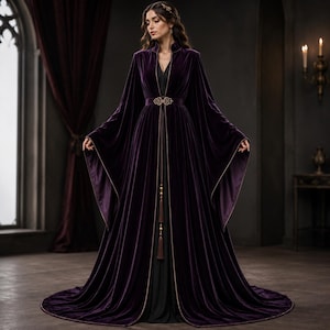 May include: A floor-length deep purple velvet robe featuring wide, flowing sleeves and a high collar. The garment is cinched at the waist with an ornate gold-toned metal clasp and includes long, dangling decorative tassels with gold accents.