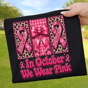 Könnte beinhalten: Ein schwarzes T-Shirt mit einer Grafik aus drei rechteckigen Feldern. Die äußeren Felder haben einen Leopardenmuster-Hintergrund mit glitzernden rosa Schleifen. Das mittlere Feld zeigt ein rosa Vichy-Muster und eine große rosa Schleife.