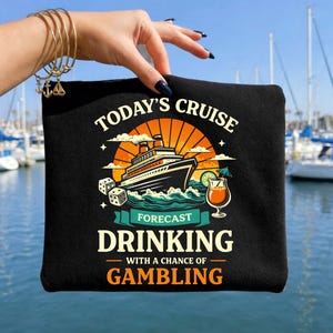 May include: Black zippered pouch with a cruise ship graphic, the text "TODAY'S CRUISE FORECAST DRINKING WITH A CHANCE OF GAMBLING". The design includes dice, a cocktail, and a sunset.