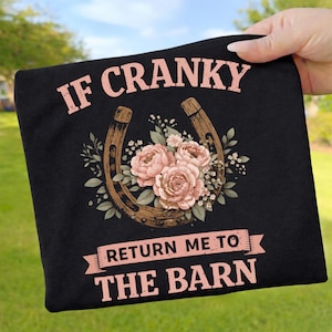 May include: Black t-shirt with the text "IF CRANKY RETURN ME TO THE BARN" in pink. The design includes a brown horseshoe with pink roses and greenery.
