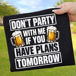Könnte beinhalten: Ein schwarzes T-Shirt mit dem weißen Text DON'T PARTY WITH ME IF YOU HAVE PLANS TOMORROW. Das Design enthält zwei Abbildungen von Bierkrügen, die mit goldenem Bier und weißem Schaum gefüllt sind und sich neben den Textzeilen befinden.