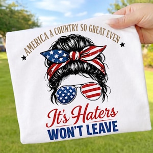 Könnte beinhalten: Weißes T-Shirt mit einer Grafik einer Frau mit Sonnenbrille und einem patriotischen Stirnband. Die Sonnenbrille und das Stirnband zeigen das Design der amerikanischen Flagge. Der Text lautet "AMERICA A COUNTRY SO GREAT EVEN It's Haters WON'T LEAVE."