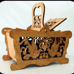May include: A wooden box with a hinged lid and a handle. The box is decorated with a carved design of two birds, a heart, and flowers. The box is made of light brown wood.