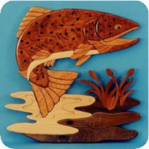 May include: A wooden wall art sculpture of a salmon leaping out of the water. The salmon is brown with dark spots and has a white belly. The water is blue and there are brown reeds in the background.
