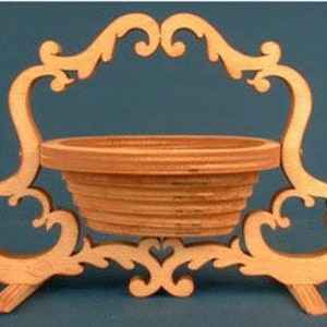 May include: A wooden decorative basket with a scrolled handle and a round base. The basket is made of light brown wood and has a natural finish.