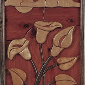 May include: A wooden wall art piece featuring a sunset scene with three white calla lilies in the foreground. The background is a red sunset with a light brown sky and clouds.