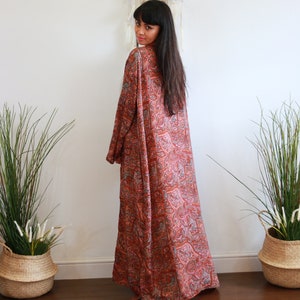 Puede incluir: Una larga t&uacute;nica fluida con estampado de paisley y un profundo escote en V. La t&uacute;nica est&aacute; hecha de una tela suave y sedosa y tiene un corte holgado. La t&uacute;nica es de un hermoso tono naranja y rosa.