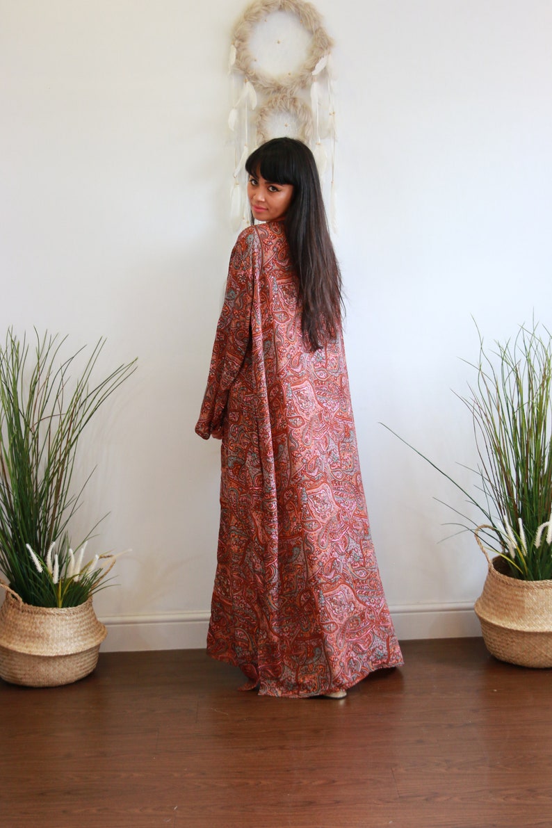 Puede incluir: Una larga t&uacute;nica fluida con estampado de paisley y un profundo escote en V. La t&uacute;nica est&aacute; hecha de una tela suave y sedosa y tiene un corte holgado. La t&uacute;nica es de un hermoso tono naranja y rosa.