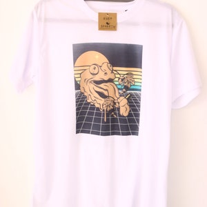 May include: White t-shirt with a graphic print of a cartoon frog wearing glasses and holding a flower. The frog is melting and dripping. The background is a retro-style grid pattern with a sunset.