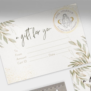 May include: A white gift certificate with a gold circle logo that says "Ruby Sparrow Flowstate Studios". The logo features a woman sitting in a yoga pose with a crescent moon on each side of her. The text "a gift for you" is written in cursive at the top of the certificate. The certificate has lines for "To", "From", "Amount", "Cert ID", and "Date".